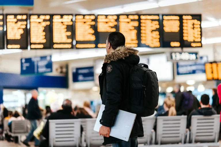 Persona en un aeropuerto esperando para tomar su vuelo con su maleta ligera